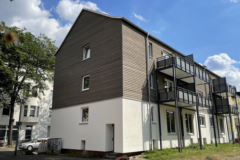 Seitlicher Blick auf ein Mehrfamilienhaus dreigeschossig mit Balkonen