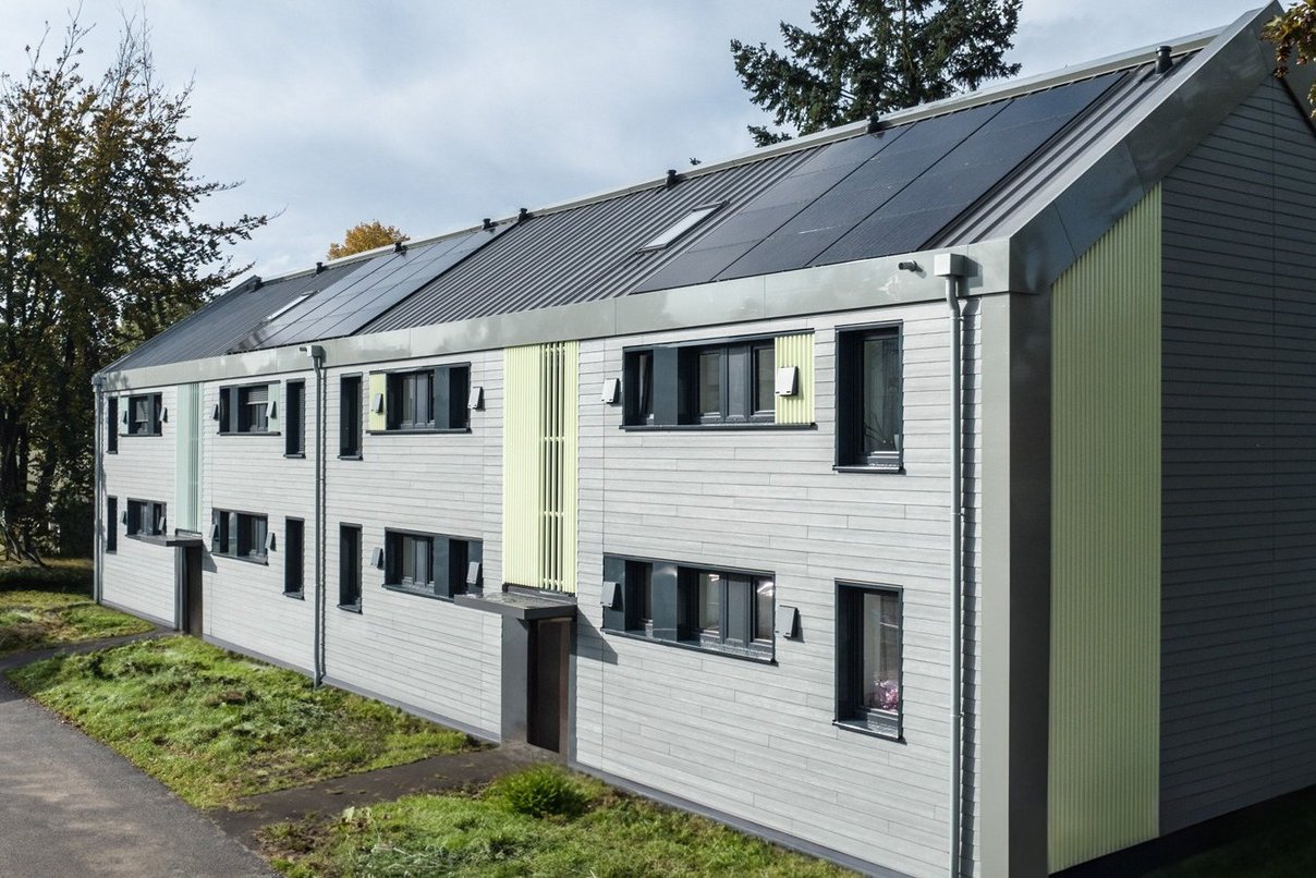 Schrägansicht saniertes Gebäude mit neuer Fassade und PV-Anlage auf dem Dach