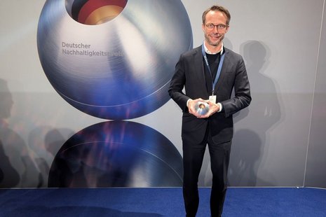 Bild zeigt: Mann mit Preis auf blauem Teppich