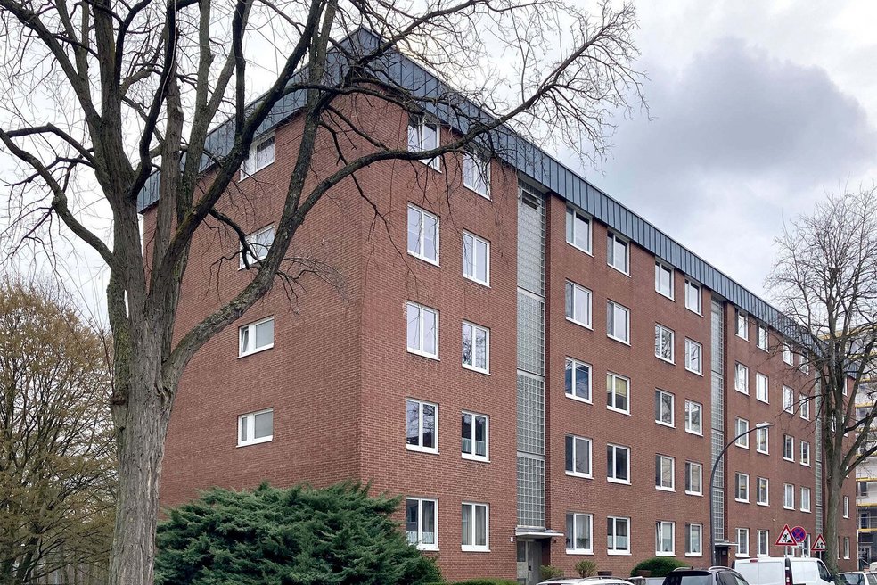 Mehrfamilienhaus fünfgeschossig, Klinkerfassade, davor parkende Autos und Bäume