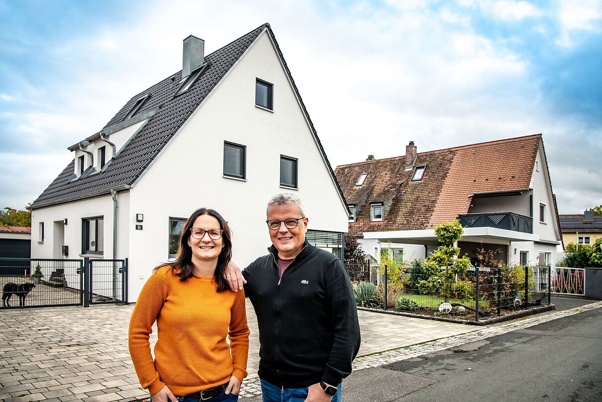 Paar mit Einfamilienhaus im Hintergrund