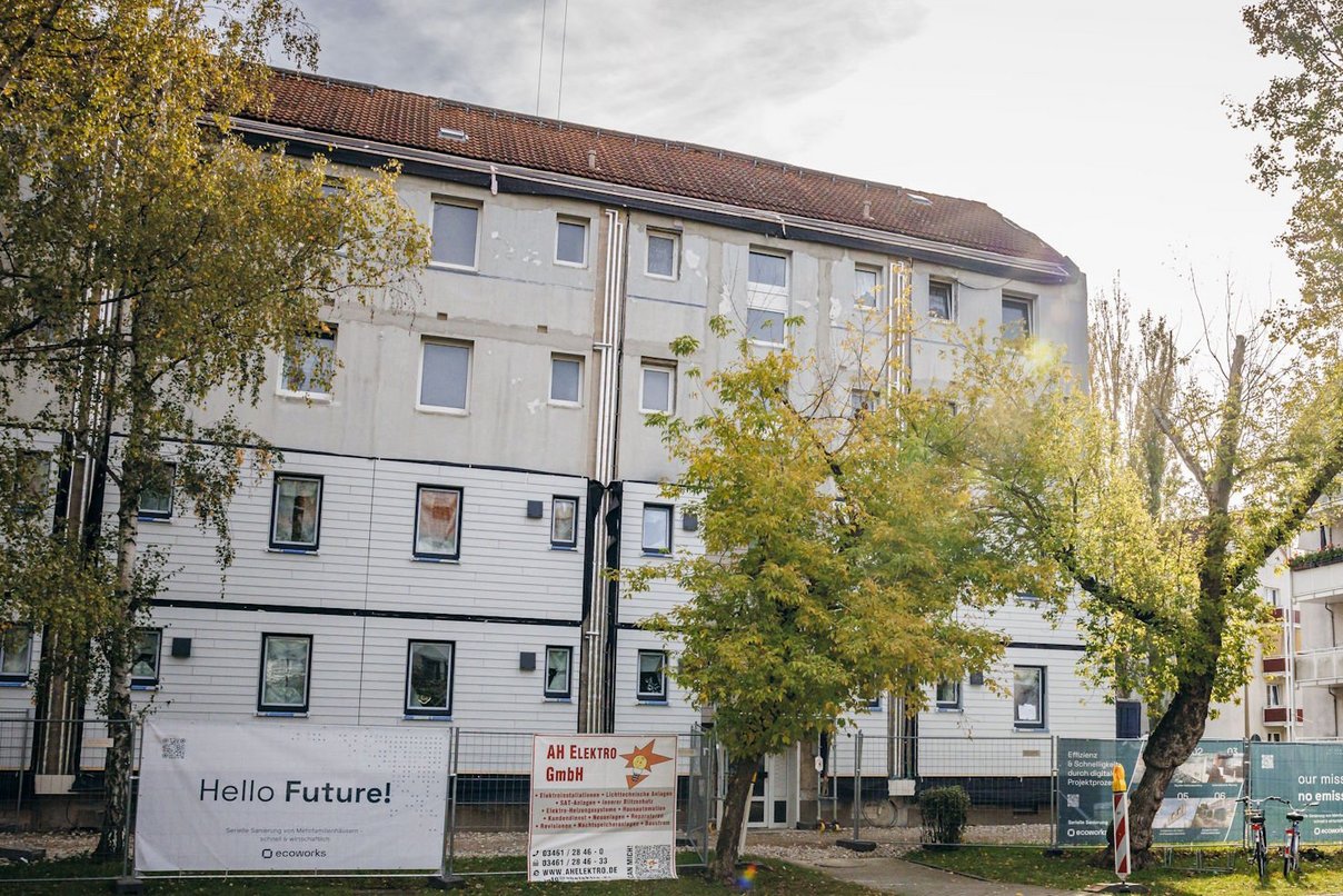 Mehrfasmilienhäuser, Laubbäume, Strasse und Fussweg