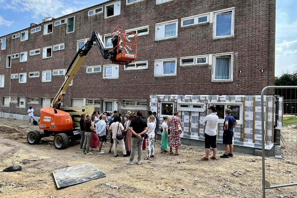 Installation von vorgefertigten Fassadenelementen aus Holz-Stroh-Modulen des Herstellers Atelier Bois – Construction an einem Mehrfamilienhaus der Wohnungsbaugesellschaft Vilogia in Tourcoing (F) Bild zeigt Menschen an Baustelle, an der vorgefertigte Fassadenelemente an einem alten Gebäude angebracht werden