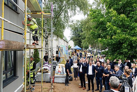 Personengruppe in Business-Outfit schaut bei einer Gebäudesanierung zu.