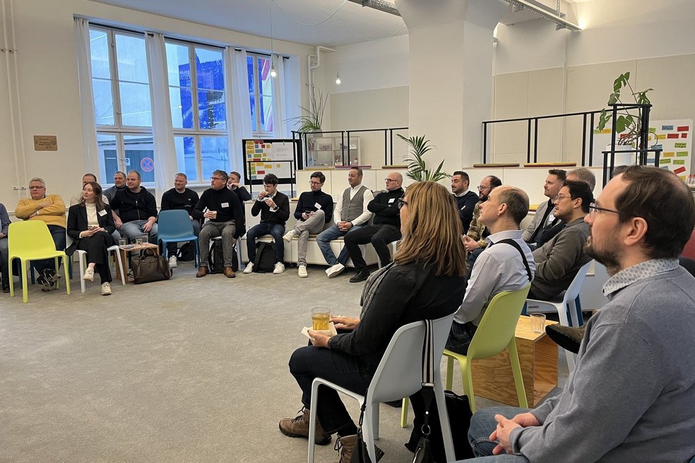 Bild zeigt: Menschen sitzen in einem Halbkreis und hören zu