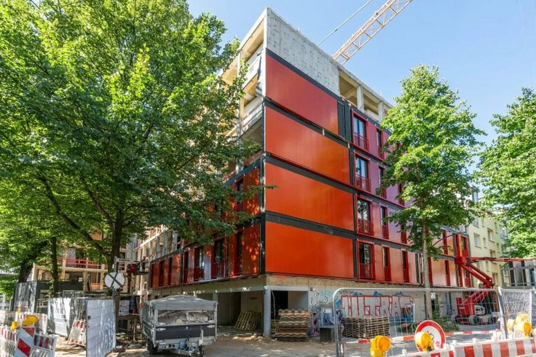 Baustelle mit Wohngebäude während Sanierung, umgeben von Laubbäumen