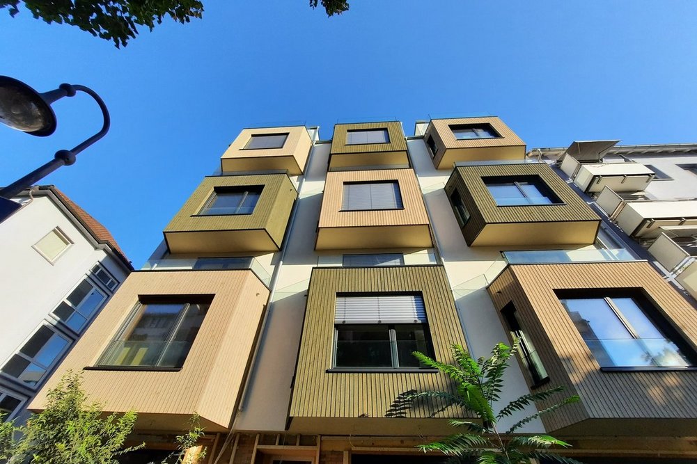Das Projekt überzeugt nicht nur optisch, sondern auch ökologisch und sozial Bild zeigt Hausansicht von unten, mehrgeschossiges Wohnhaus mit Erkern