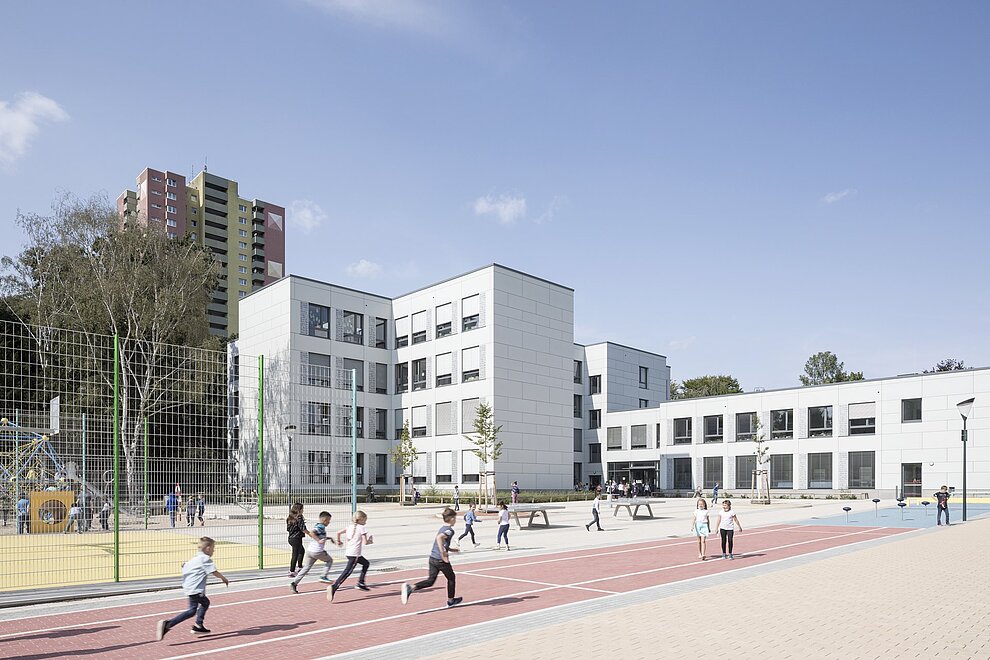 Schulgebäude mit rennenden Kindern auf dem Schulhof