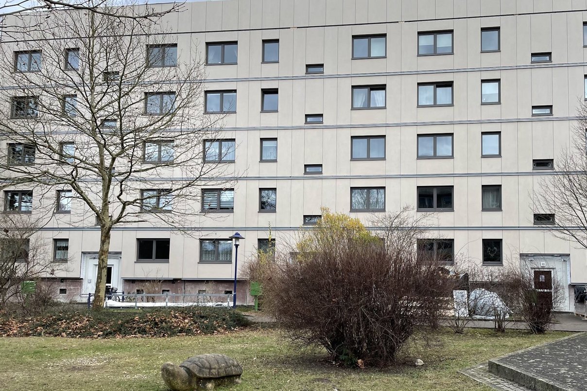 Plattenbau saniert, im Vordergrund Grünflächen mit Spielgeräten
