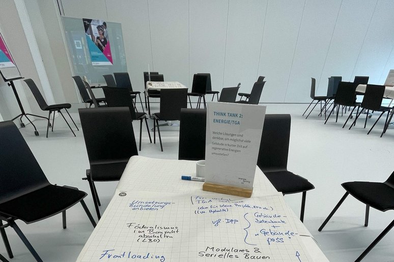 Tisch und schwarze Stühle in einem Workshopraum, auf dem Tisch Flipchart-Papier mit Notizen