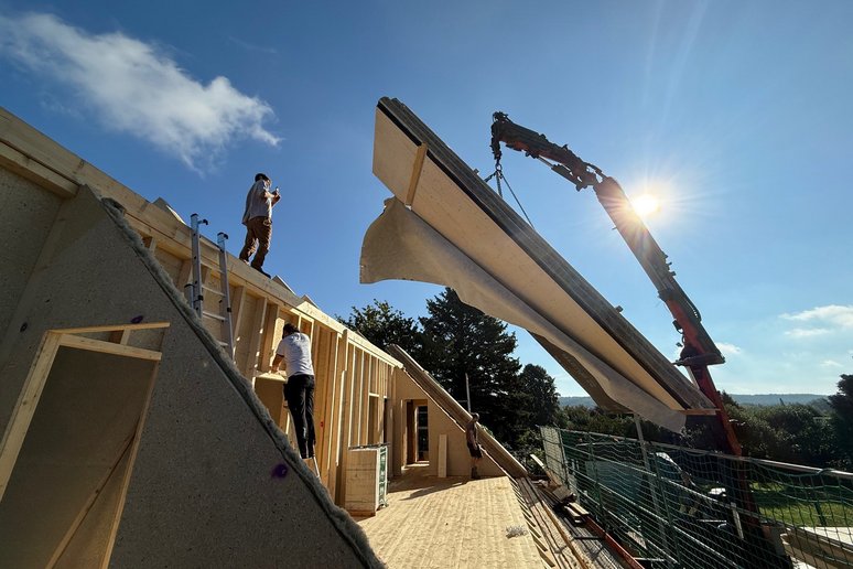 Bild zeigt offenen Dachstuhl, viel Holz und Kran