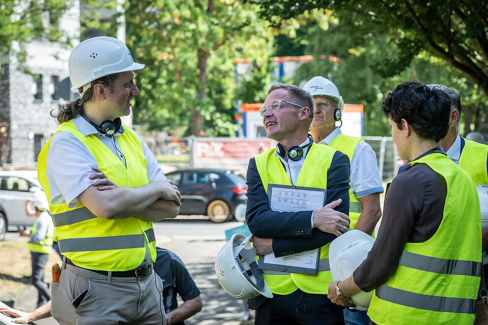 Personen mit gelben Sicherheitswesten im Gespräch