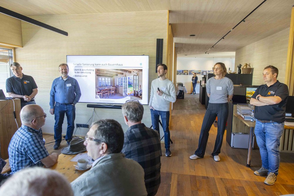 Bild zeigt: 5 Personen vor Menschen in einem Raum mit Bildschirm im Rücken